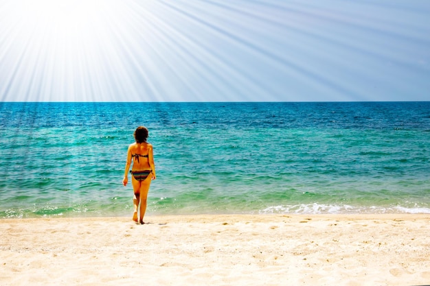 Young woman walking to swim in the sea