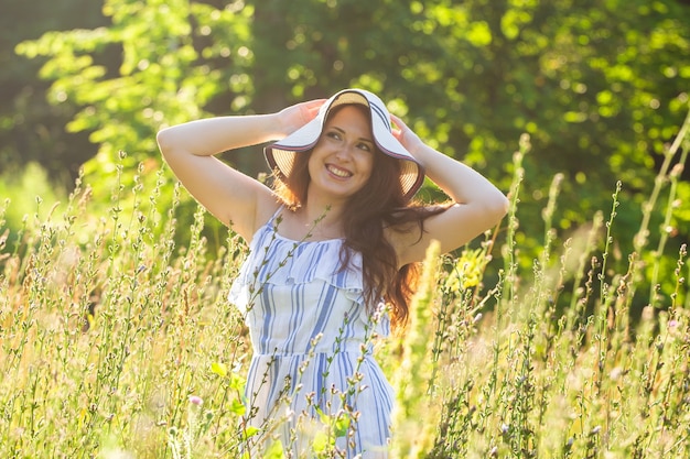 Young woman walking among wildflowers on sunny summer day. Concept of the joy of communicating with summer nature