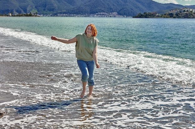 Young woman walks barefoot on beach