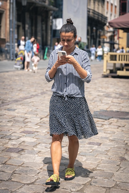 A young woman walks with a smartphone in the city