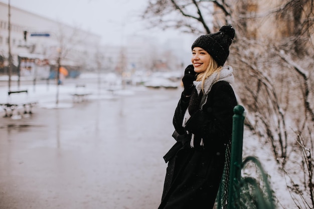 Young woman in warm clothes using mobile phone on a winter day