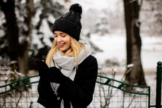 Young woman in warm clothes using mobile phone on a winter day