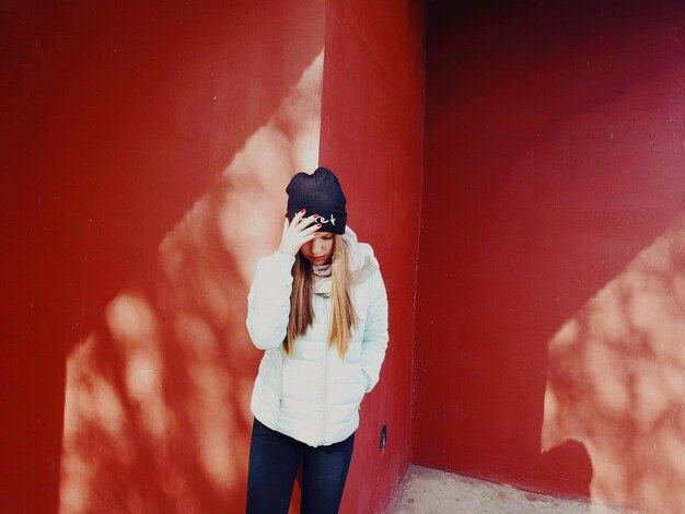 Photo young woman in warm clothing standing by red wall