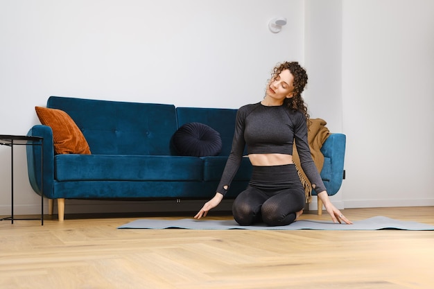 Young woman warming up neck muscles before doing exercises at home