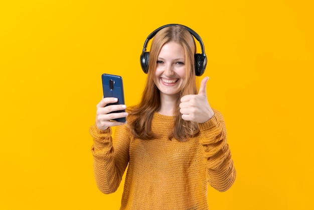 Young woman watching video clips on the phone in wired headphones in casual