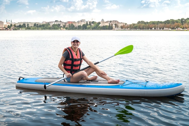 Young woman wear life vest paddle boarding on a lovely lake at summer hot day