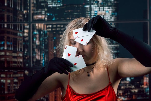 Young woman wear red shiny dress black hat holding cards of aces