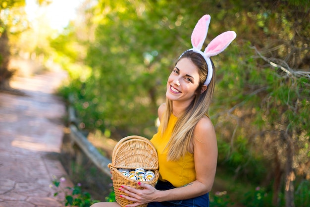 Young woman wearing bunny ears and with colorful Easter egg at outdoors