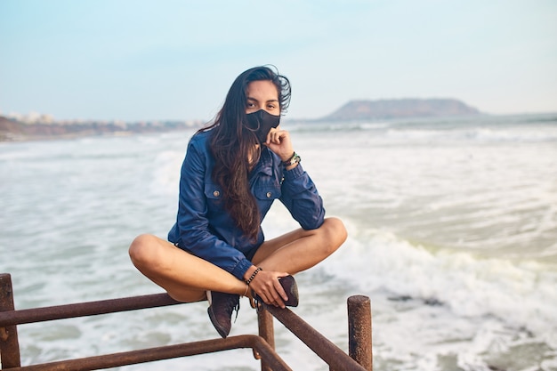 young woman wearing face mask on the pier. outdoor sport at sunset time. Free woman resting at sunset