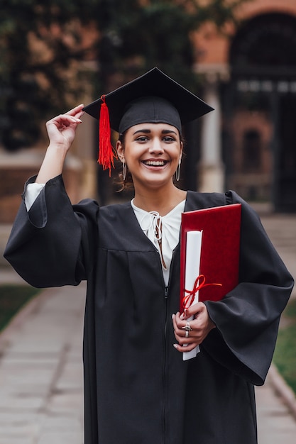 Young woman wearing graduate uniform holding degree