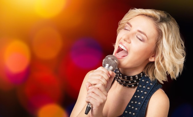 Young woman wearing hat singing into microphone