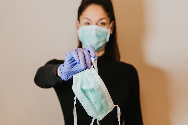 Young woman wearing and holding a facemask with gloves