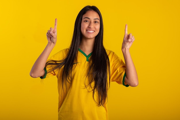 Young woman wearing the official uniform shirt of the Brazilian soccer team at the 2022 Qatar Cup in studio photo Brazilian fan