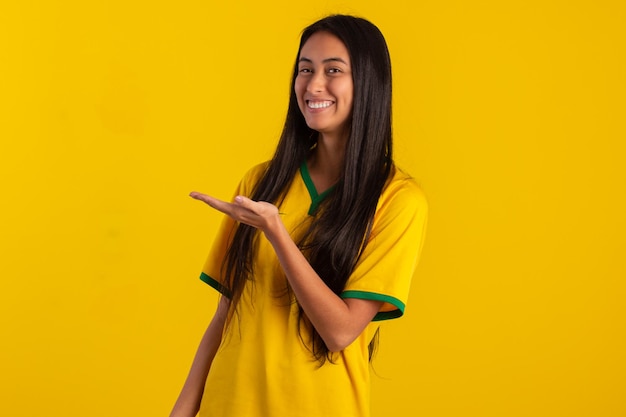 Young woman wearing the official uniform shirt of the Brazilian soccer team at the 2022 Qatar Cup in studio photo Brazilian fan