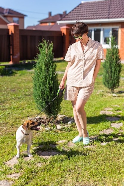 Young woman wearing pajama with her dog on backyard the concept of animals and friendship or pet own