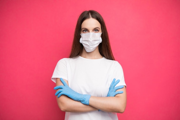 Young woman wearing protective mask on face and medical gloves keeping arms crossed. Confident girl