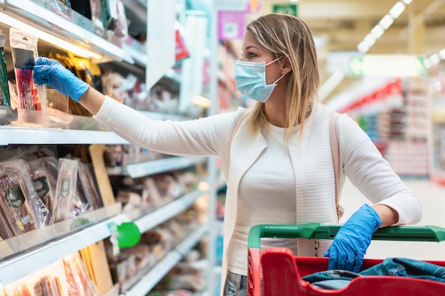 Young woman wearing protective mask in supermarket during coronavirus outbreak