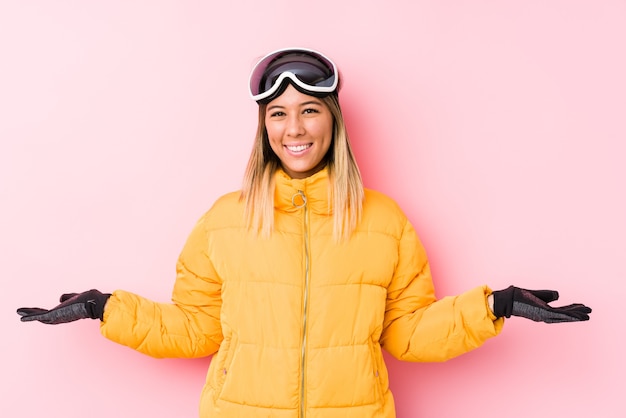 Photo young woman wearing a ski clothes in a pink wall showing a welcome expression