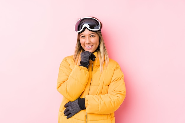 Young woman wearing a ski clothes smiling happy and confident, touching chin with hand