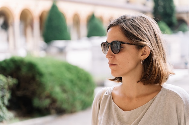 Young woman wearing sunglasses facing the front at the cemetery in Bologna, Italy