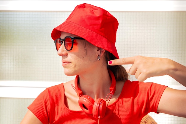 Photo a young woman wearing sunglasses is sitting pointing her finger to the side