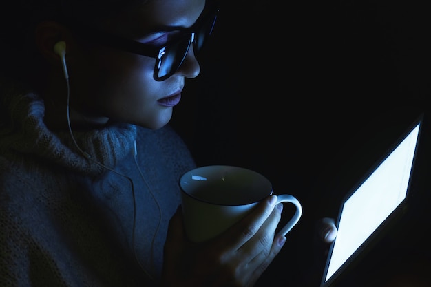 Young woman wearing a warm pullover is using tablet PC