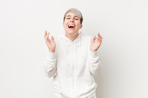 Young woman wearing a white hoodie joyful laughing a lot.