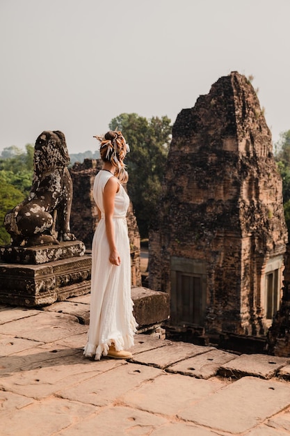 Young woman wearing white robe dress in ancient Khmer ruins Angkor Wat