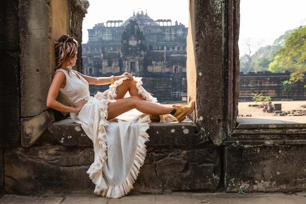 Young woman wearing white robe dress in ancient Khmer ruins Angkor Wat