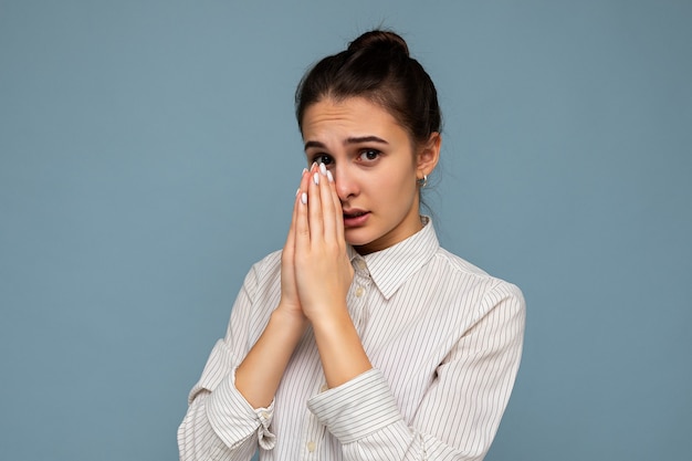 Young woman wearing white shirt and holding hands together in pray