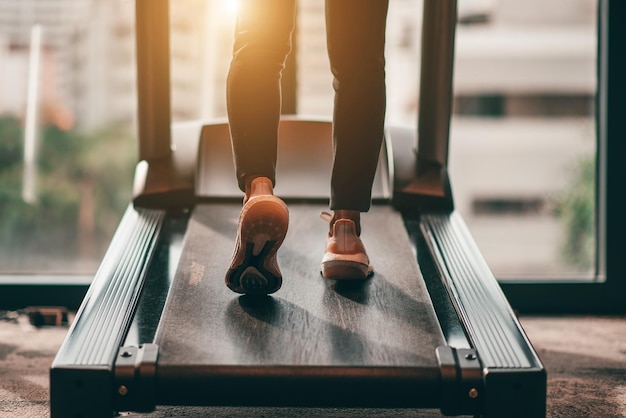 Young woman wearing white sport shoes walking on treadmill in the morning with sunlight She training for cardiovascular endurance and good health with in fitness center