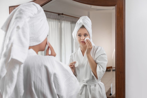 Young woman in a white bathrobe with a towel on her head