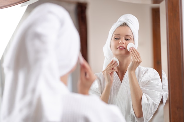 Young woman in a white bathrobe with a towel on her head