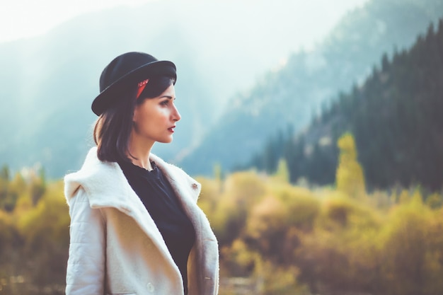 A young woman in a white coat walking in nature looks away Take cover from the autumn cold