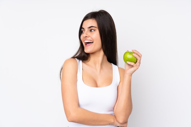 Young woman over white wall with an apple and happy