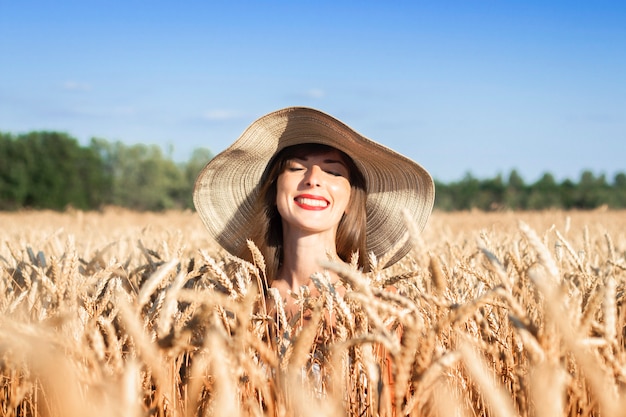 Young woman in a wide-brimmed hat peeks out of wheat