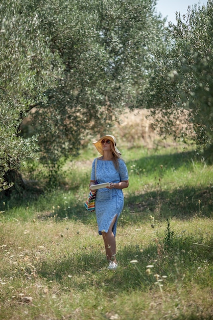 A young woman in a wide-brimmed hat and sunglasses, wandering in a summer park