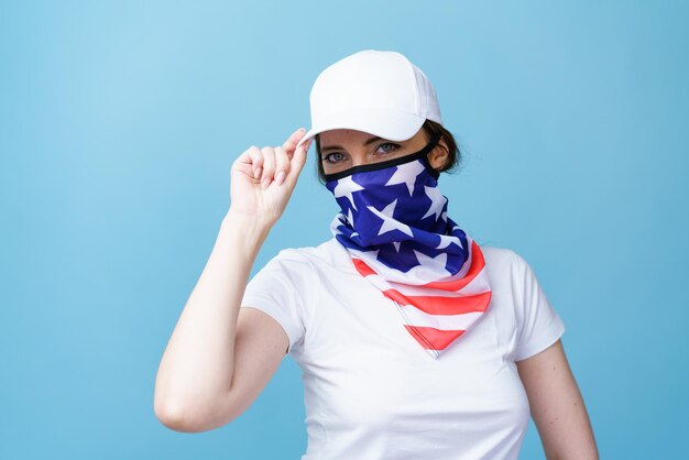 Young woman with America flag mask on her face in white tshirt and cap