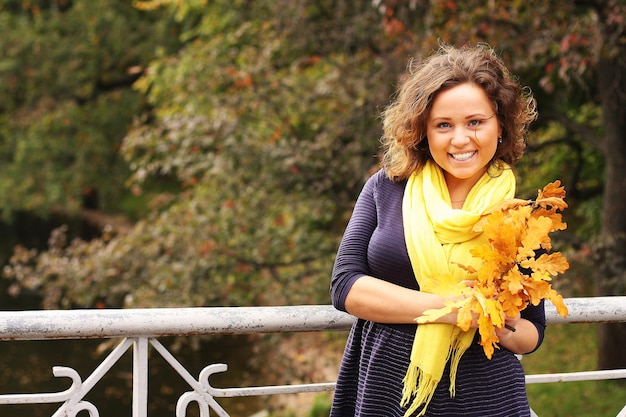 Young woman with autumn leaves in park