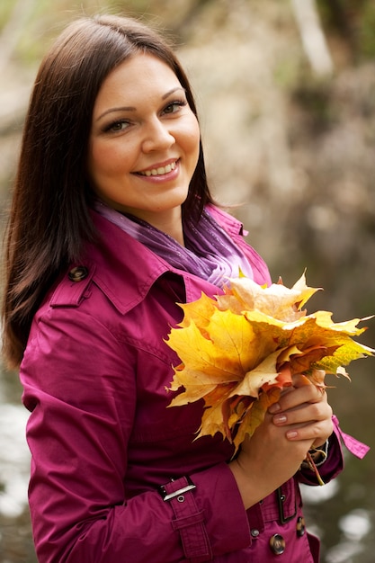 Young woman with autumn leaves in park