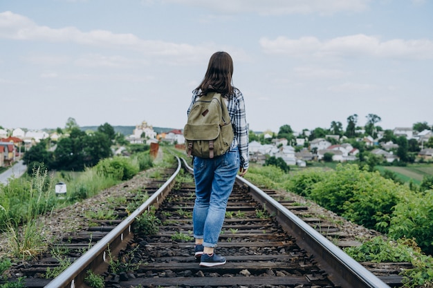 Young woman with a backpack on a railway track.