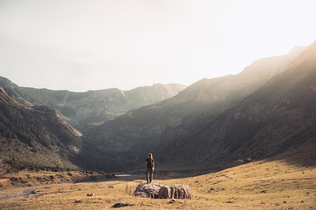 Young Woman With A Backpack on The Top Of a rock in a Beautiful wild Landscape Discovery Travel