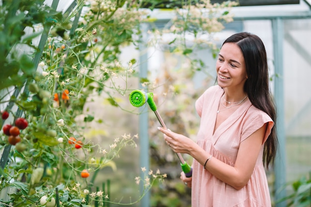 Young woman with basket of greenery and vegetables in the greenhouse.