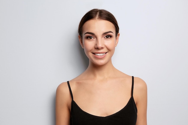 Young woman with beautiful eyebrows on light background