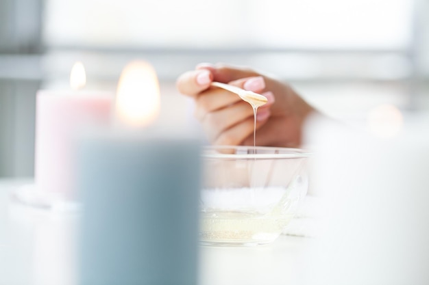 Young woman with beautiful hands putting some wax on them to remove all their hair