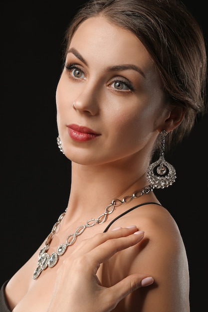 Young woman with beautiful jewellery on black