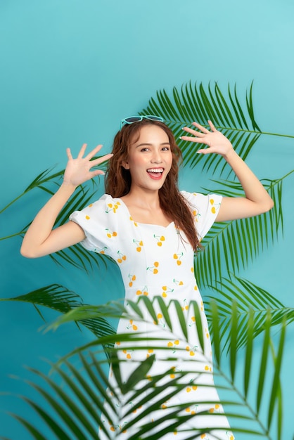 Young woman with beautiful makeup and tropical leaves on blue background