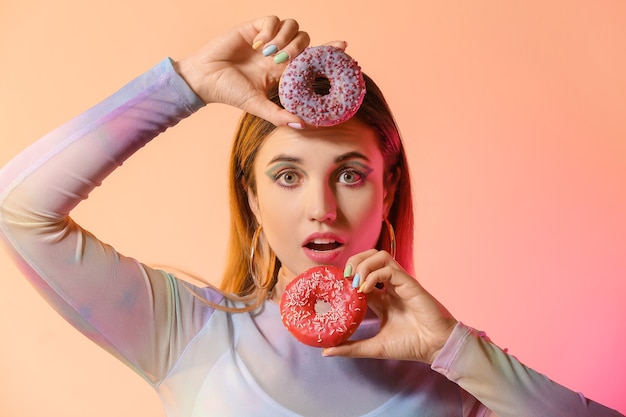 Young woman with beautiful manicure and donuts on pink