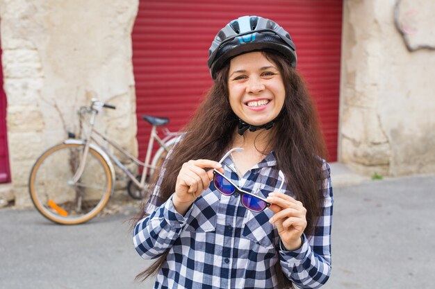 Young woman with bicycle looking camera on the background red doors