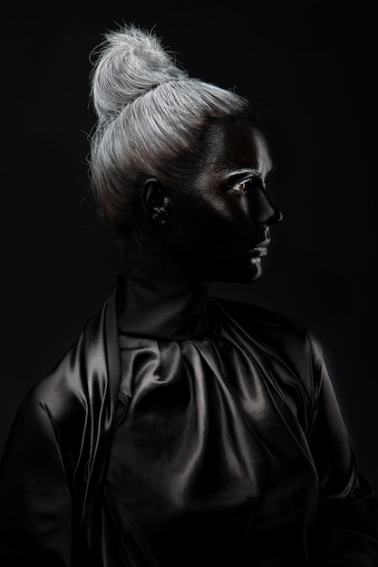 Young woman with black face paint on a black background